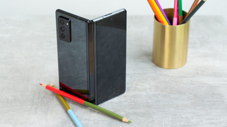 Samsung Galaxy Z Fold 2 Ein Samsung Galaxy Z Fold2 steht auf einem Tisch, daneben liegen ein paar Buntstifte.