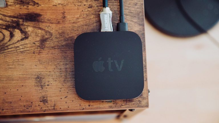 Auf einem Holztisch steht ein verkabelter Apple TV