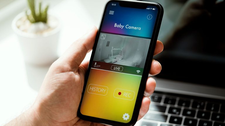 Eine Hand hält ein Smartphone, auf dem eine Babyphon-App geöffnet ist.