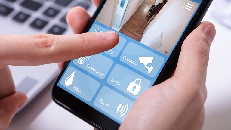Smartphone Upcycling Eine Hand hält ein Smartphone, auf dem die Benutzeroberfläche einer Überwachungsapp zu sehen ist. Darin ist ein Kamerabild zu sehen, das einen Flur zeigt.