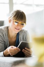 Eine Person liegt auf einem Sofa und schaut auf ein iPad.