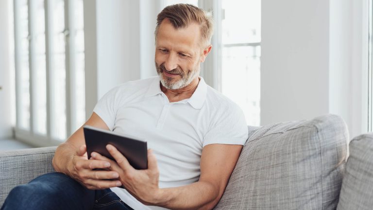 iPad Modelle Eine Person sitzt auf einem Sofa und schaut auf ihr iPad.
