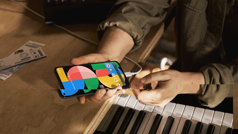 Eine Person hält das Google Pixel 5a in der Hand, das per USB-C aufgeladen wird.