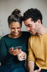 Zwei Personen schauen zusammen auf ein Smartphone.