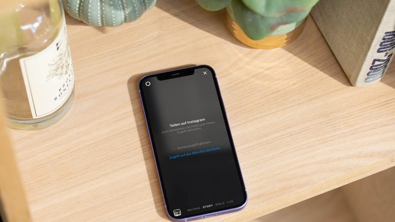 Instagram Story erstellen Ein iPhone mit aktivierter Instagram-Kamera liegt in einem Regal.