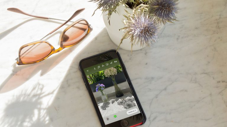 Instagram Story erstellen Ein iPhone liegt auf einer Marmor-Oberfläche. Auf dem Bildschirm ist das Teilen eines Bildes als Story bei Instagram zu sehen.