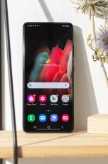 Ein Samsung Galaxy steht auf einem Regal neben Pflanzen.