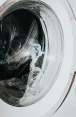 Eine Waschmaschine in der Nahaufnahme. Zu sehen sind Wasser und Kleidung in der Trommel.