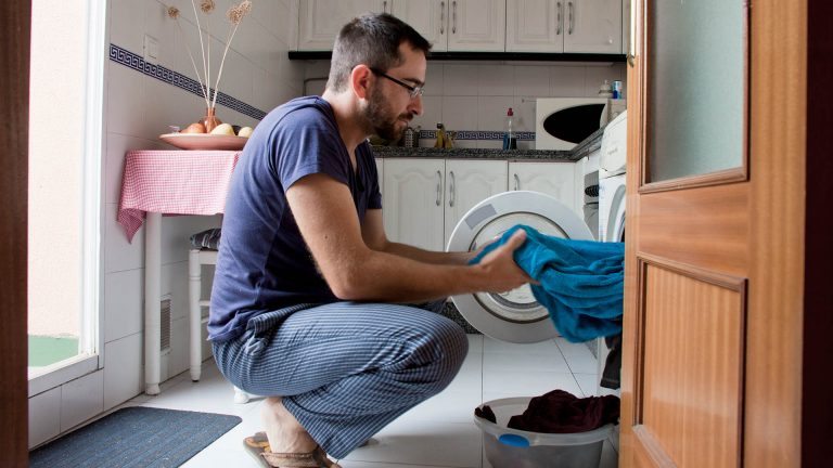 Waschmaschine pumpt nicht от Eine Person holt ein Handtuch aus einer Waschmaschine.