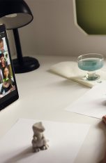 Ein Kind sitzt vor einem iPad, auf dem ein FaceTime-Call mit mehreren Teilnehmern läuft, und bemalt Figuren.