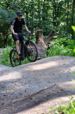 Eine Person fährt auf einem E-MTB über kleine Hügel auf einem Bike-Trail.
