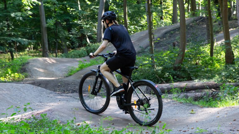 E-MTBs Eine Person fährt auf einem elektrischen Mountainbike über einen Bike-Trial.