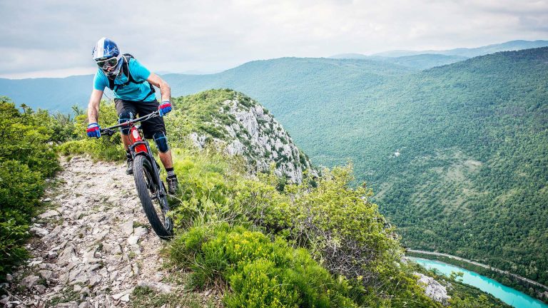 E-MTBs Eine Person fährt einen hohen Berg mit einem Mountainbike herunter.
