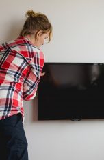 Eine Person montiert einen Flachbildfernseher an der Wand.
