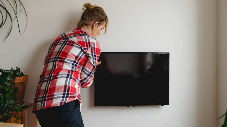 Eine Person montiert einen Flachbildfernseher an der Wand.