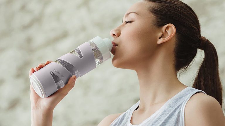 Bellabeat Spring Eine Person trinkt aus der smarten Trinkflasche Bellabeat Spring.