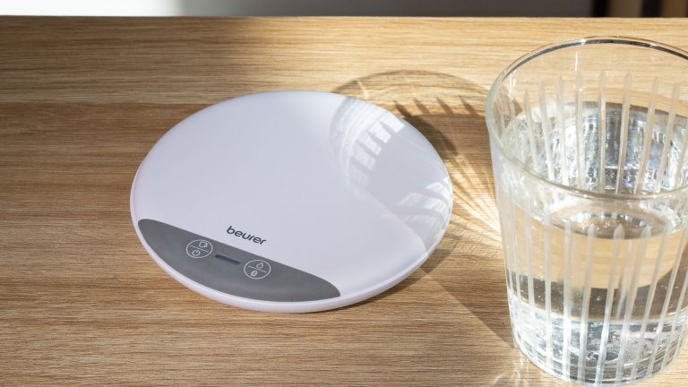 Beurer DM20 Im Fokus des Bilds liegt der Beurer Trinkmanager. Neben ihm steht ein volles Glas Wasser.