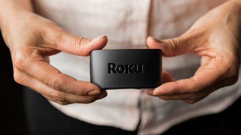 Eine Person hält einen Roku Express in die Kamera.