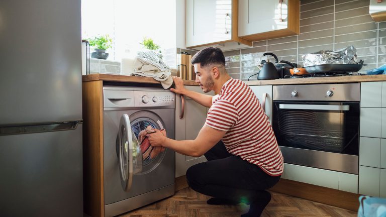 Waschmaschine schleudert nicht Eine Person bestückt die Waschmaschine mit Wäsche.