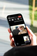Eine Person hält ein iPhone in der Hand. Auf dem Bildschirm ist ein laufendes FaceTime-Gespräch zu sehen.