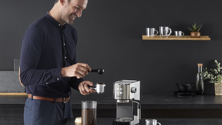 Krups Virtuoso XP442C Eine Person tampert gerade Kaffee. Vor ihr steht die Krups Virtuoso XP442C.