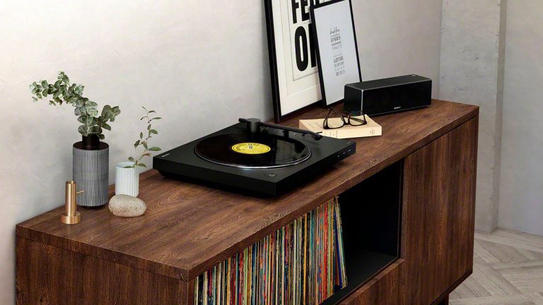 Sony PS-LX310BT Ein moderner Plattenspieler in schlichter Optik steht auf einem Sideboard. In das offene Fach sind Schallplatten einsortiert