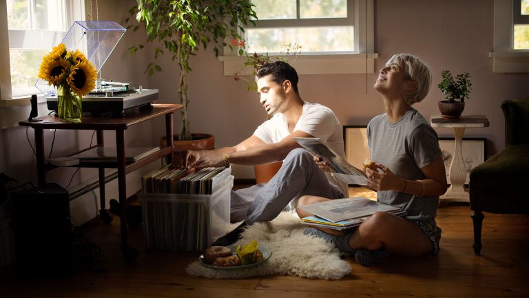 Zwei Personen sitzen auf dem Fußboden vor einer Plattenkiste und schauen sich die Schallplatten an.