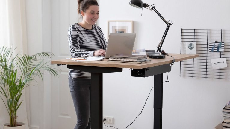 Boho Office Homedesk Eine Person steht am höhenverstellbaren Schreibtisch von Boho Office.