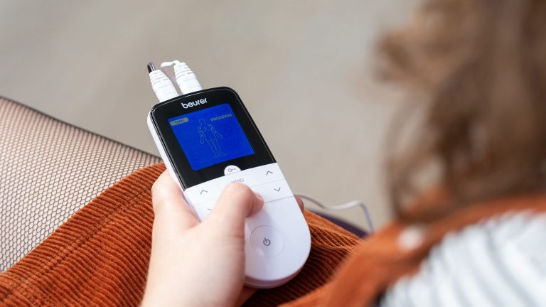 Beurer EM 49 Eine Person hält ein TENS-Gerät in den Händen. Das Display zeigt die Programmauswahl an.