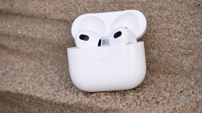 Apple AirPods (3. Gen.) Das Ladecase samt AirPods der dritten Generation steht auf einer Sanddüne.
