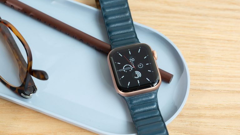 Apple Watch 7 Eine Apple Watch SE liegt eingeschaltet neben einer Brille in einer Schale.