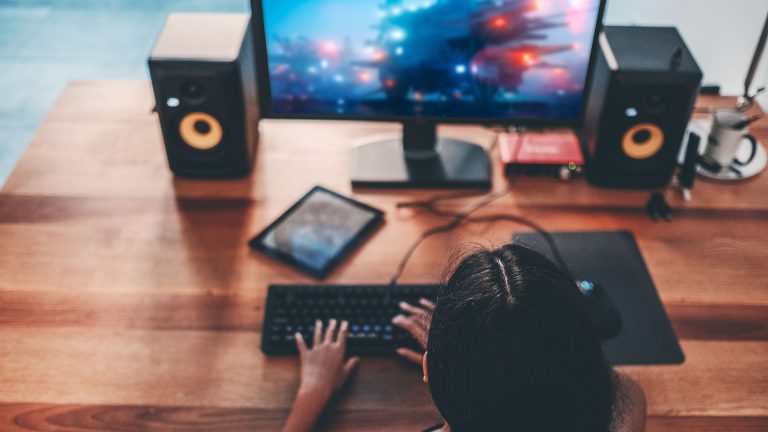 Gaming-Monitore Eine Person sitzt an einem Tisch und schaut auf einen Monitor, auf dem gerade eine Spielszene zu sehen ist.
