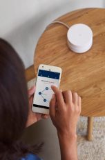 Eine Person richtet einen WLAN-Router von Google ein.