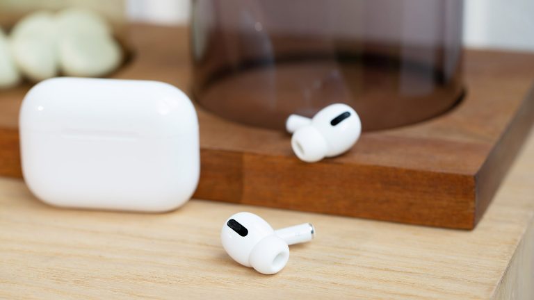 Apple AirPods Pro Die Apple AirPods Pro liegen neben dem Ladecase auf einem Tisch.