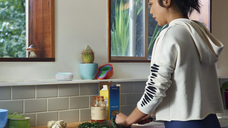 Amazon Echo Dot Eine Person arbeitet in der Küche und spricht dabei mit einem Echo-Lautsprecher.