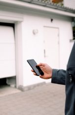 Eine Person öffnet mit ihrem Smartphone eine smarte Garagentür.