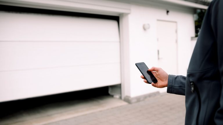 Eine Person öffnet mit ihrem Smartphone eine smarte Garagentür.
