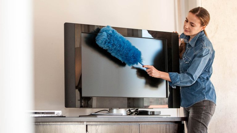 Fernseher reinigen Eine Person macht mit einem Staubwedel einen Fernseher sauber.