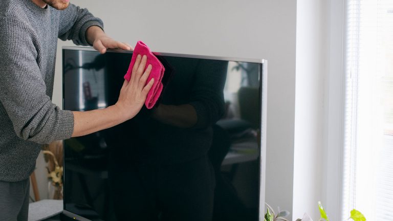 Fernseher reinigen Eine Person reinigt mit einem Mikrofasertuch einen Fernseher.