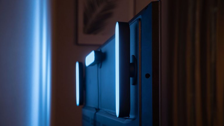 Philips Hue Play Drei schwarze Philips Hue Play sind hinten an einem Fernseher angebracht.