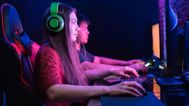 Zwei Personen sitzen vor Bildschirmen und spielen etwas.
