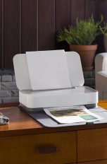 Der HP-Drucker Tango X steht auf einer Kommode. In der Ablage liegt ein Ausdruck.