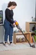 Eine Person saugt mit einem Akkusauger einen Läufer.