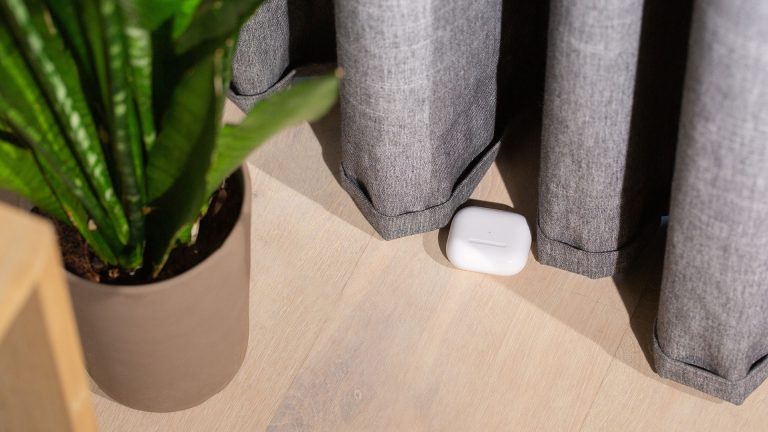 AirPods unter Android nutzen Ein AirPod-Case liegt unter einem Vorhang auf dem Boden.