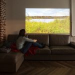 Eine Person sitzt auf einem Sofa vor der Projektion eines Beamers.