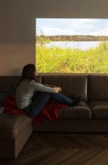 Eine Person sitzt auf einem Sofa vor der Projektion eines Beamers.