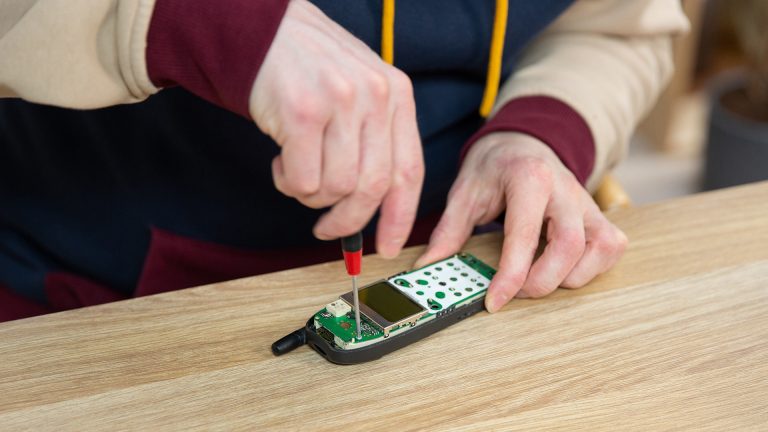 Nokia 5110 Bilderrahmen Mit einem Torx-Schraubendreher löst eine Person eine Schraube auf der Platine des Nokia 5110.