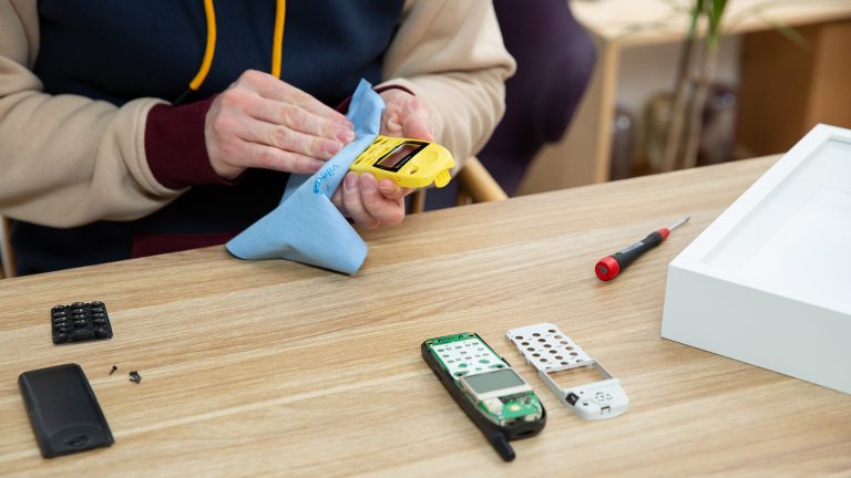 Nokia 5110 Bilderrahmen Eine Person putzt mit einem Tuch das Cover des Nokia 5110.