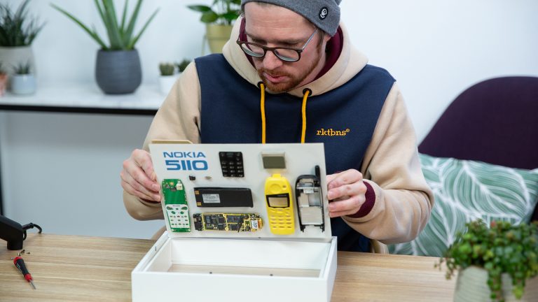 Nokia 5110 Bilderrahmen Eine Person legt Rahmenrückseite samt aufgeklebter Bauteile zurück in den Objektrahmen.