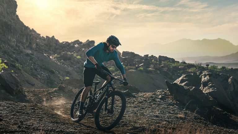 Garmin Fenix 7 Eine Person fährt auf einem Mountainbike einen Berg hinunter. Sie trägt dabei eine Garmin Fenix 7.